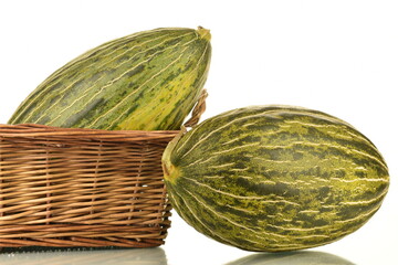 Two juicy ripe melons with a basket of vines, close-up, isolated on white.