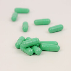 A capsule of green pills, isolated on a white background