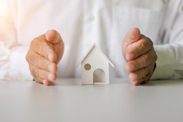 Businessman's hands to protect the safety of homes. Architecture, safety, security, real estate and property concept - close up of hands protecting house or home model.