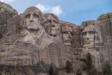 Obraz premium Black Hills, Keystone, SD, USA - May 31, 2008: Mount Rushmore. Near view of the famous sculpture of 4 presidents. Gray granite under blue cloudscape.