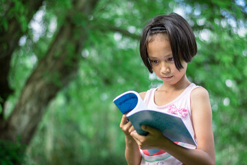 a girl reading a book intently in the park
