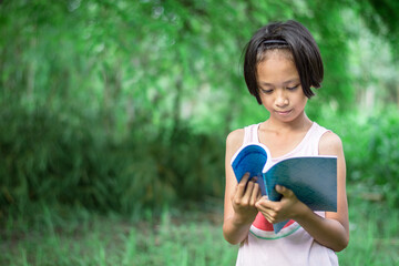 a girl reading a book intently in the park