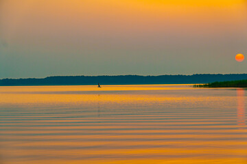 Naklejka na ściany i meble sunset at coast of the lake. Nature landscape. Nature in northern Europe. reflection, blue sky and yellow sunlight. landscape during sunset.