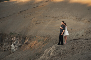 Young man and girl are higging on the bank of lake. Couple in love spend time forever together