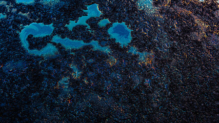 Oil stain on Asphalt road after rain, color Gasoline fuel spots on Asphalt Road