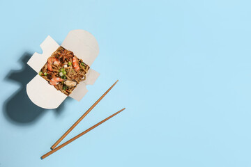 Noodle wok with chopsticks on light blue background, flat lay. Space for text