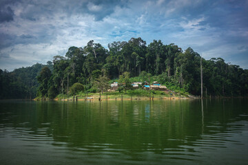 a rain forest scenic of orang asli village in the lake with cloudy sky background.