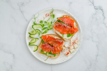 Bruschetta with salmon and cheese on white plate on marble table top view