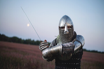 A knight with a sword battles on the battlefield on a dark sky background. - obrazy, fototapety, plakaty