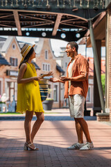 side view of stylish interracial couple talking on city street