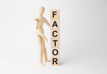 Wooden mannequin near tower of cubes with word factor on table against light background