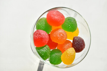 Marmalade in sugar in a glass vase on a white background