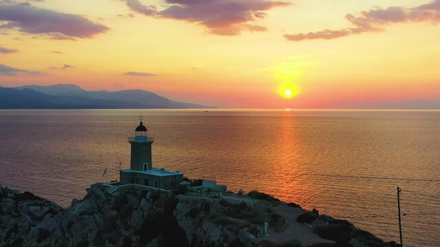 Drone flying by a small light house on a hill top in Melagkavi in Greece. It is a very beautiful evening, where the sun is setting over the Mediterranean sea in the background. 