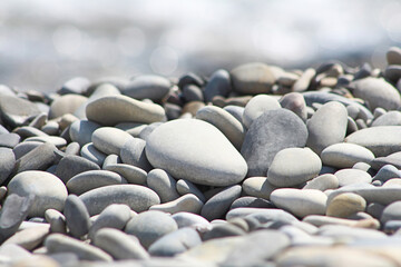 Sea pebble stones. Blurred out of focus sun lights bokeh natural background, wallpaper.
