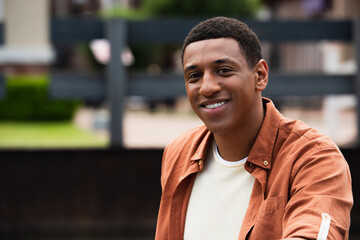 Fototapeta premium young african american man looking at camera and smiling outdoors