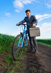 Businessman with a bicycle posing in a green grass field - business concept for freedom, vacation or freelance. Beautiful spring nature.