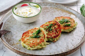 Fried pancakes made of potatoes and zucchini on a plate. The idea of Breakfast for vegetarians, close-up