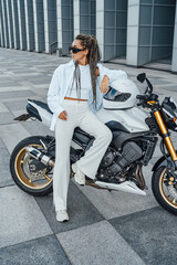 Fototapeta na wymiar Woman with sunglasses posing around bike and building