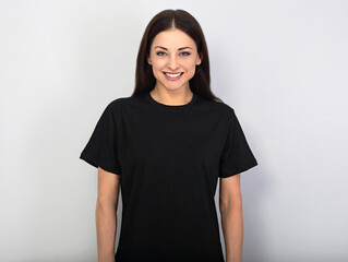 Happy toothy smiling woman posing in blank black t-shirt on blue background - 446674650