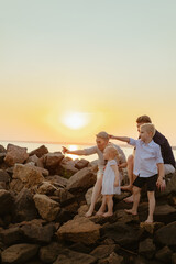 lovely caucasian family: pregnant woman and her husband kissing and children child enjoy sunset on beach