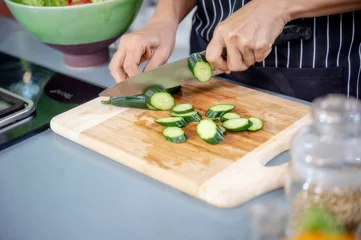 Foto op Canvas Hand of woman chef slicing cucumbers in luxuly kitchen. © Chaiphorn