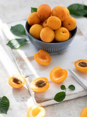 Fresh apricots in a blue bowl on a white wooden background