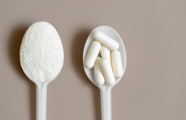 Collagen on a beige background close up. Collagen powder and pills in spoons. Supplement for the health of the skin, bones and joints. View from above. Space for text.