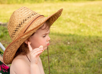 A small child in a farm straw hat stands with a thumbs up