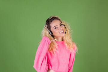 Young blonde woman with long curly hair in pink sweater on green background call centre worker manager happy positive smiling cheerful