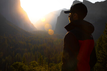 Man standing in front of the forest at sunrise