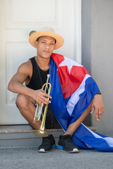 Latino man with the cuban flag holding a trumpet: Selective focus Music and diversity concept.