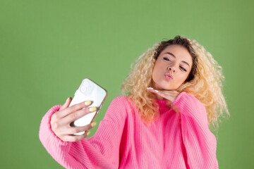 Woman in pink sweater on green background holding mobile phone posing take photo selfie