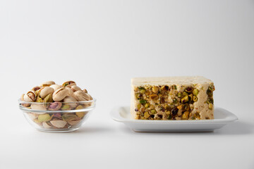 Organic halva with pistachios on a white plate isolated on white. Traditional middle eastern sweets. Jewish, turkish, arabic oriental national dessert. Turkish delight concept. Natural vegan product.