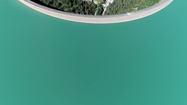Aerial view of the Austria Schlegeis Stausee dam pan up revealing the Alps the structure is a barrier that stops the flow of surface water and is used as hydropower to generate electricity 4k quality