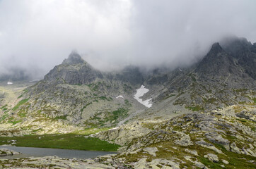 Jagged and sharp ridges rock emerge from the mist above and rain clouds at High Tatras National Park, Slovakia