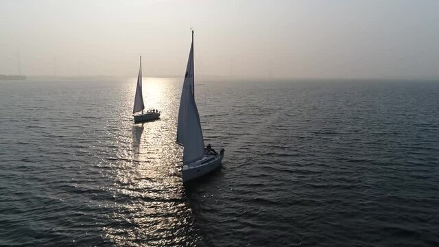 Aerial bird view footage of two sloops on quiet and lonely ocean the type is sailboat with a single mast typically having only one headsail in front of boat and another mainsail aft 4k quality