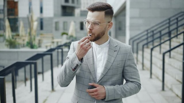 Business man smokes IQOS cigarettes on the street