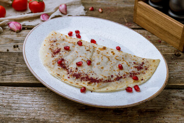 plate with Qutab with meat and pomegranate on old wooden table