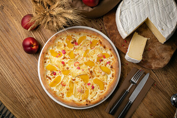 Pizza with cheese and peaches on a wooden table
