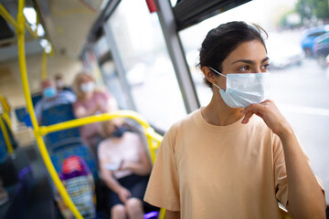 Indian Woman ride in public transport bus or tram in medical face mask