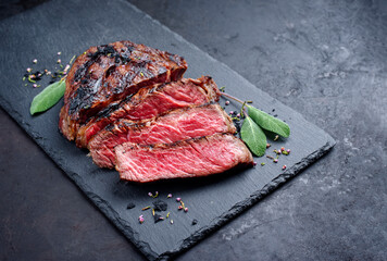 Barbecue dry aged wagyu rib-eye beef steaks with herb and black salt served as top view on a black board