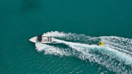 Aerial photo of extreme power boat donut water-sports cruising in high speed in tropical emerald bay