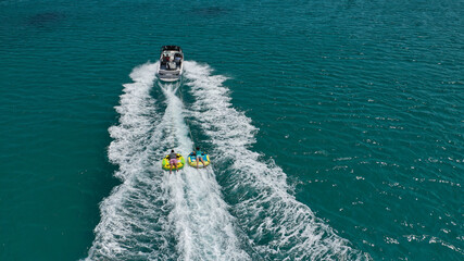 Aerial photo of extreme power boat donut water-sports cruising in high speed in tropical emerald bay