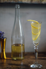 french 75 champagne cocktail with lemon twist garnish in flute glass with bottle gold