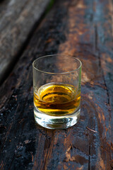 Glass of strong scotch single malt whisky on old log soaked in creosote
