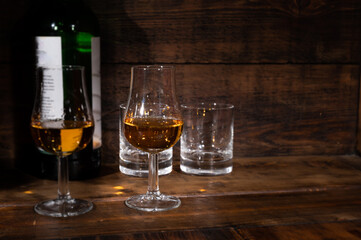 Glasses of strong scotch single malt whisky served on dark wooden table in old pub