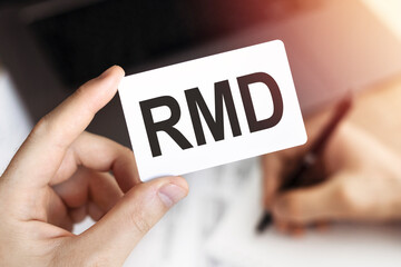 Business concept. Card with letters RMD - Required Minimum Distribution.