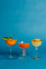 trio three citrus cocktails orange grapefruit lemon on teal blue background 
