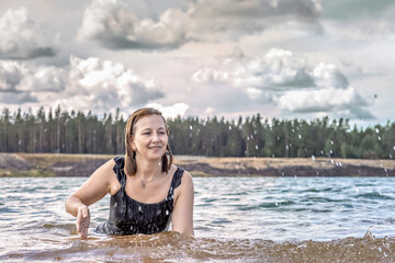 Portrait of a young woman in the water. Swimming in the lake,splashes.