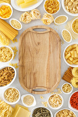 Pasta. Various kinds of uncooked pasta and noodles over stone background, top view with copy space for text. Italian food culinary concept. Collection of different raw pasta on cooking table